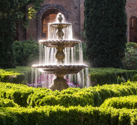 A fountain in lush gardens on a sunny day.