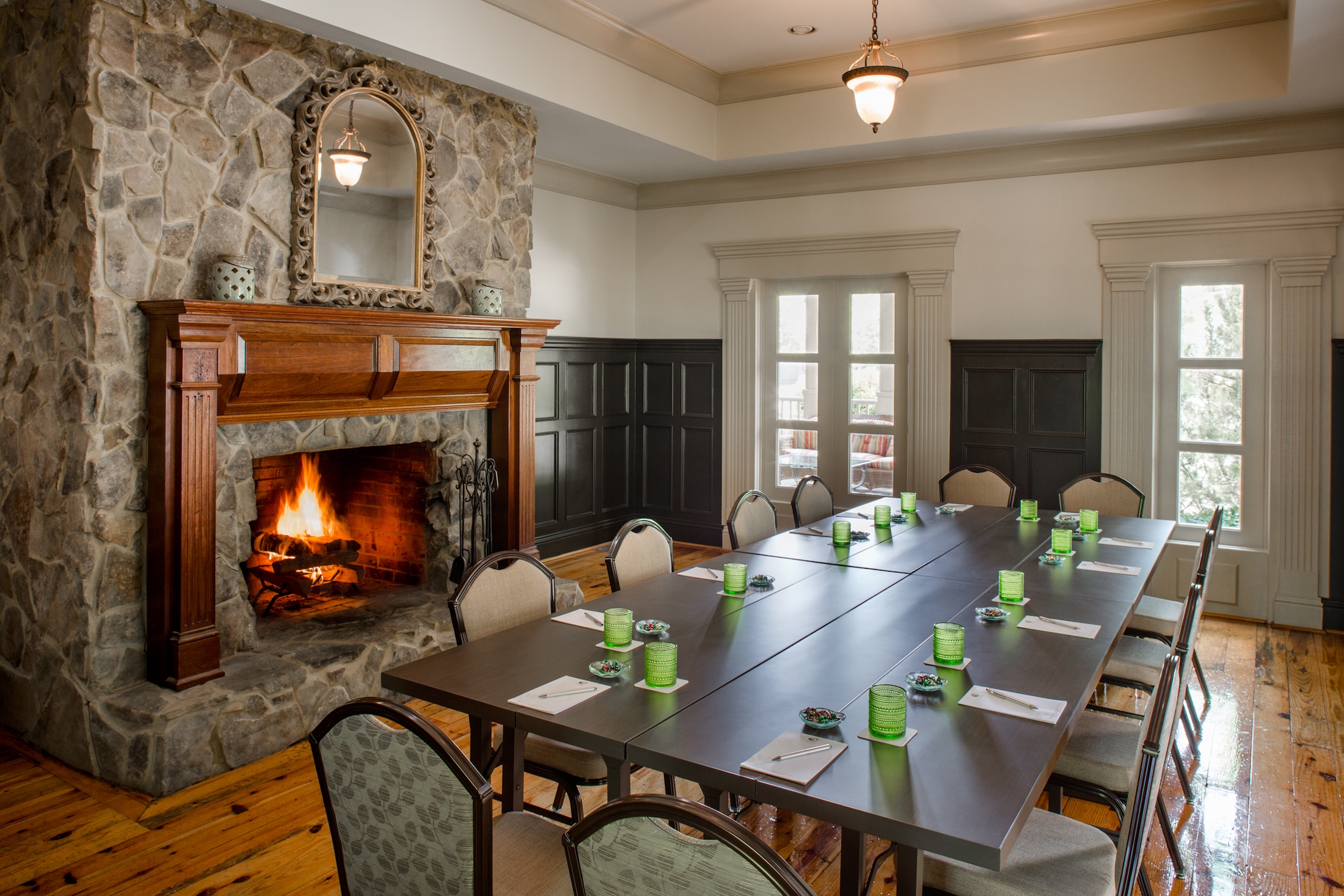The interior of Birch Cottage, a fire in the large fireplace behind a meeting table at Barnsley Resport.