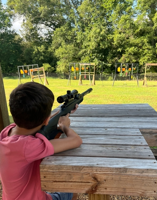 boy holding an air rifle and pointing at targets