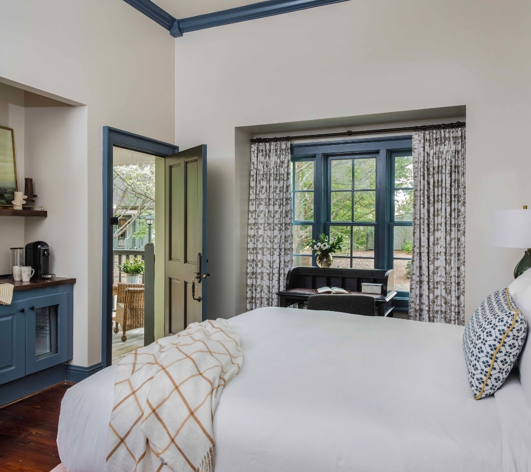 a bedroom with a desk and open door leading outside