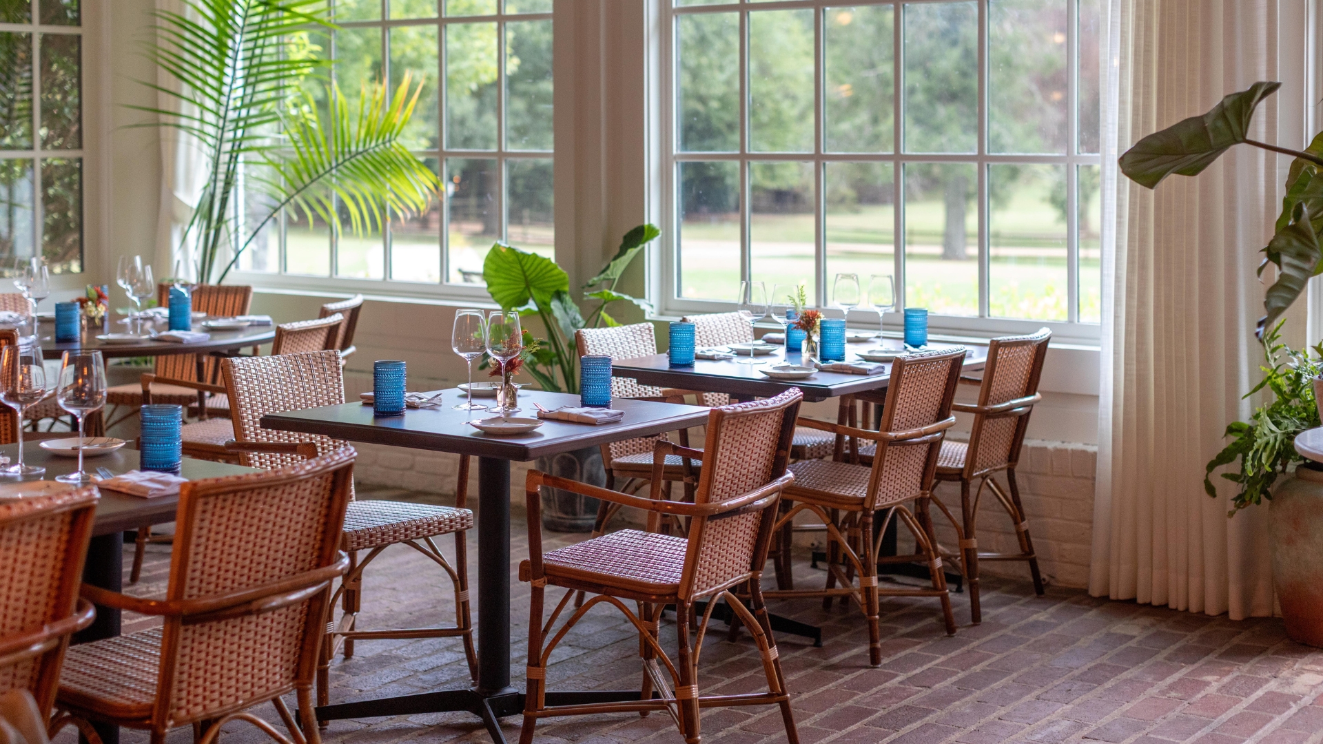 room of table and chairs with large windows and plants