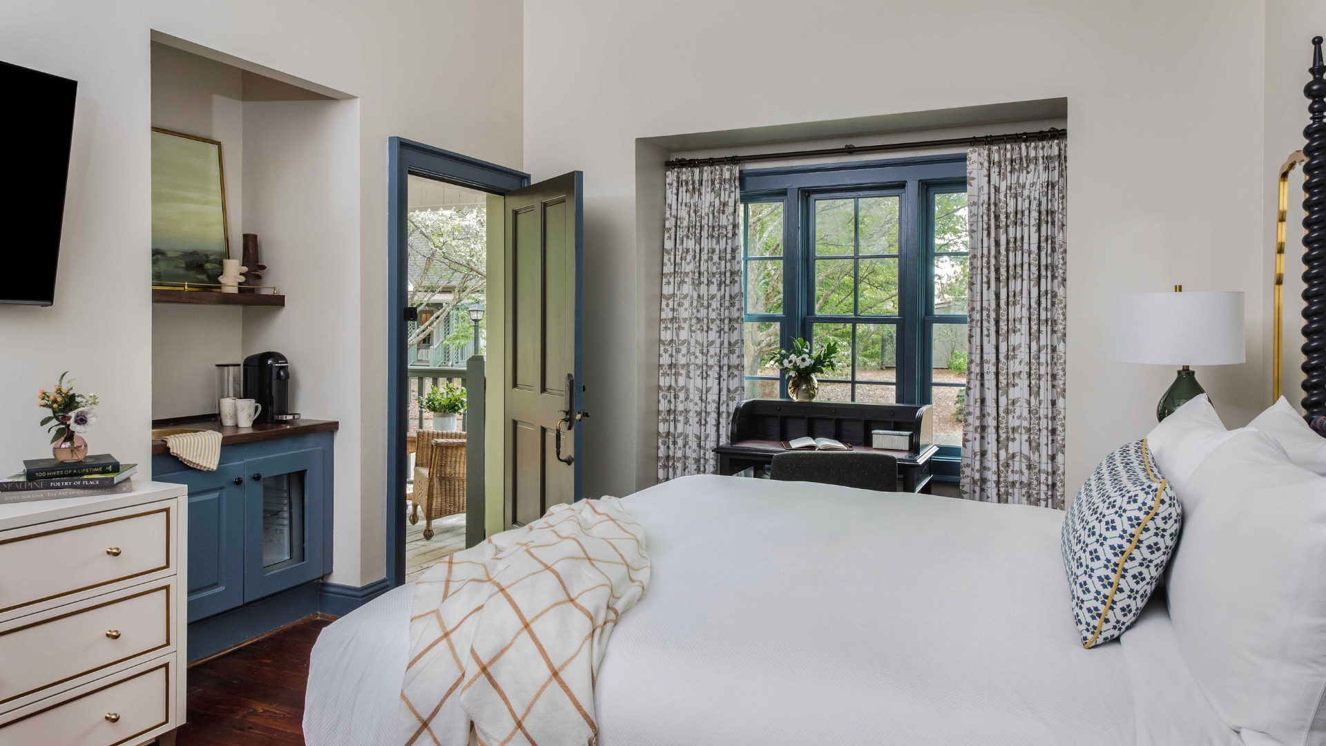 a bedroom with a desk and open door leading outside