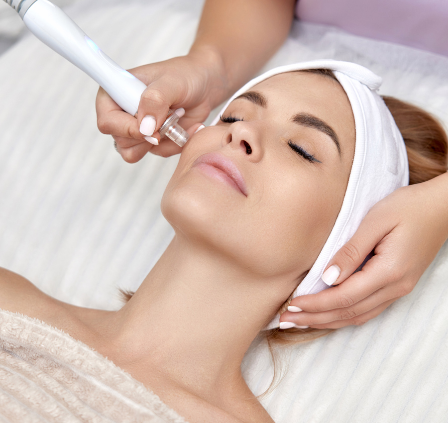 A spa worker applies a facial product to a woman's face.