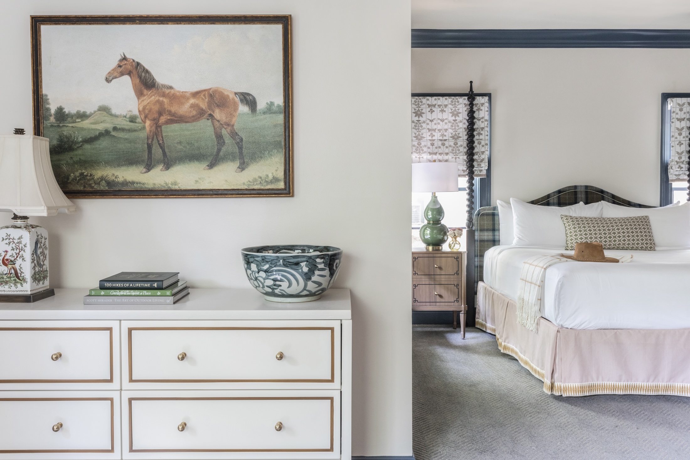 A dresser with artwork and books on top, with the king in the background in the Julia Cottage at Barnsley Resort.