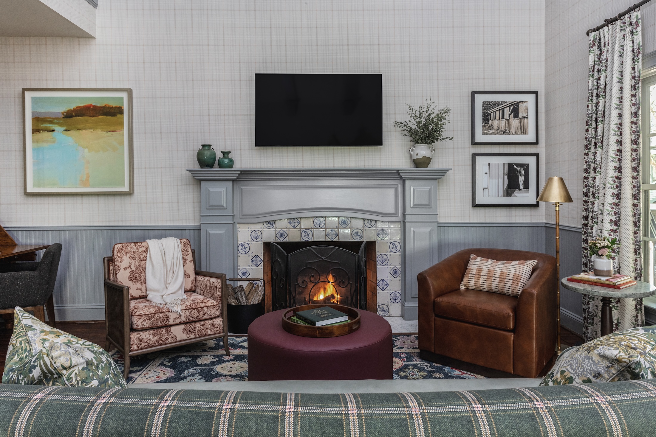 A living area in the Julia Cottage at Barnsley Resort, with plush couch, arm chairs with a fire in the fireplace.