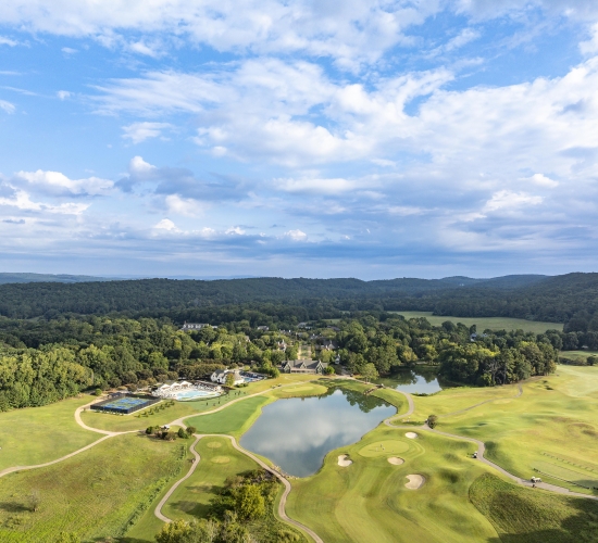 Aerial of a golf course, two pools, putt putt course, and pickleball courts at a resort.