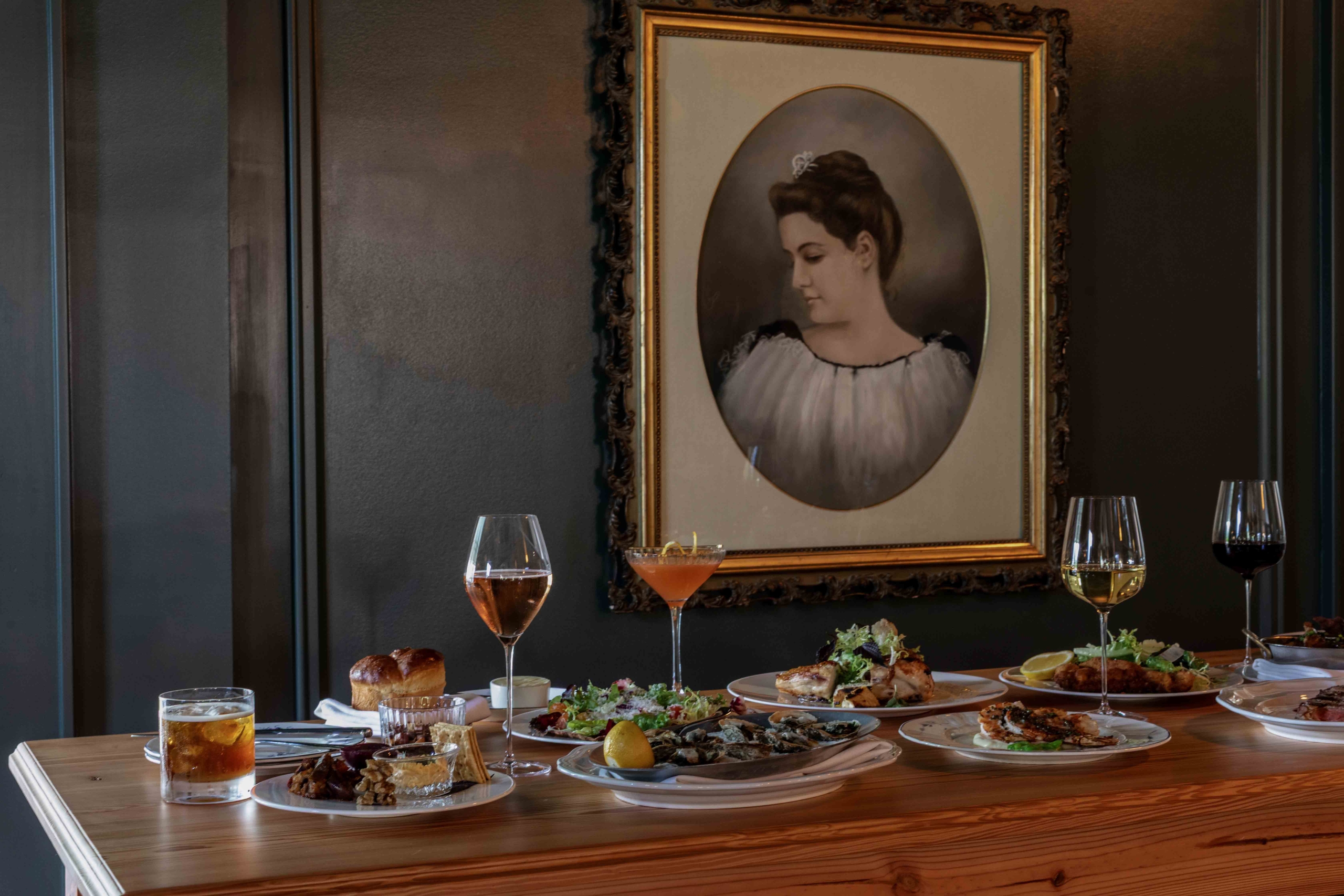 Portrait of woman on wall behind a table of various dishes.