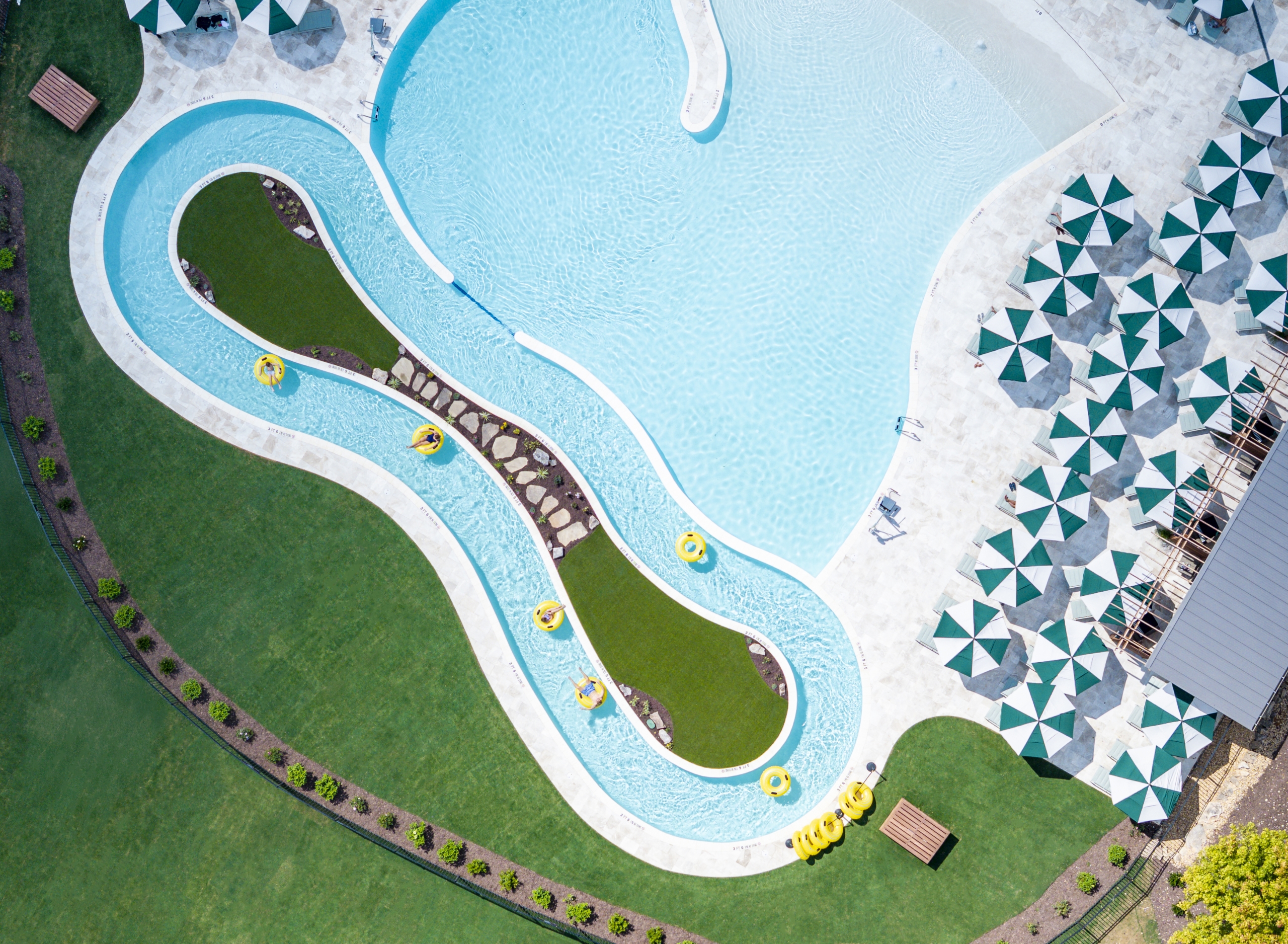 aerial view of a pool with a lazy river and striped umbrellas