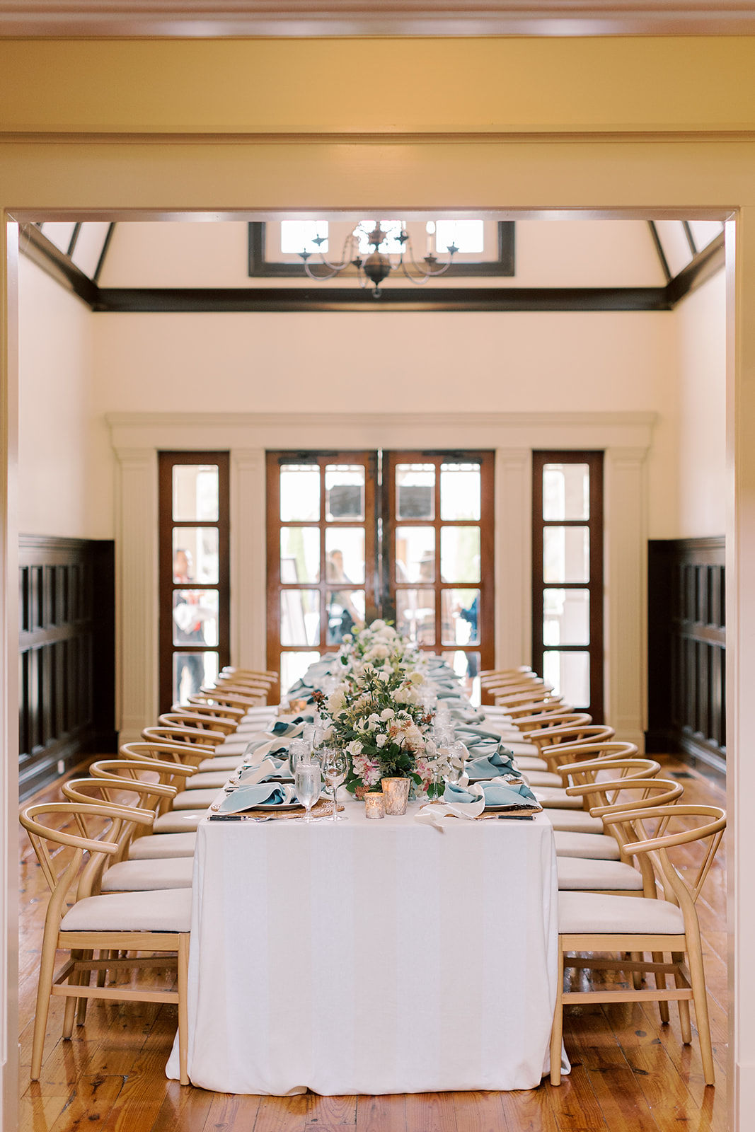 The interior of Birch cottage set up for a wedding reception. A long banquet table is set, including lush floral arrangements.