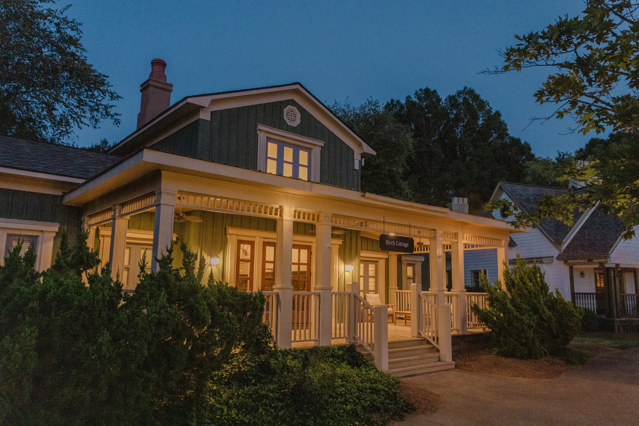 The exterior of Birch Cottage at dusk, inviting lights are lit on the porch.