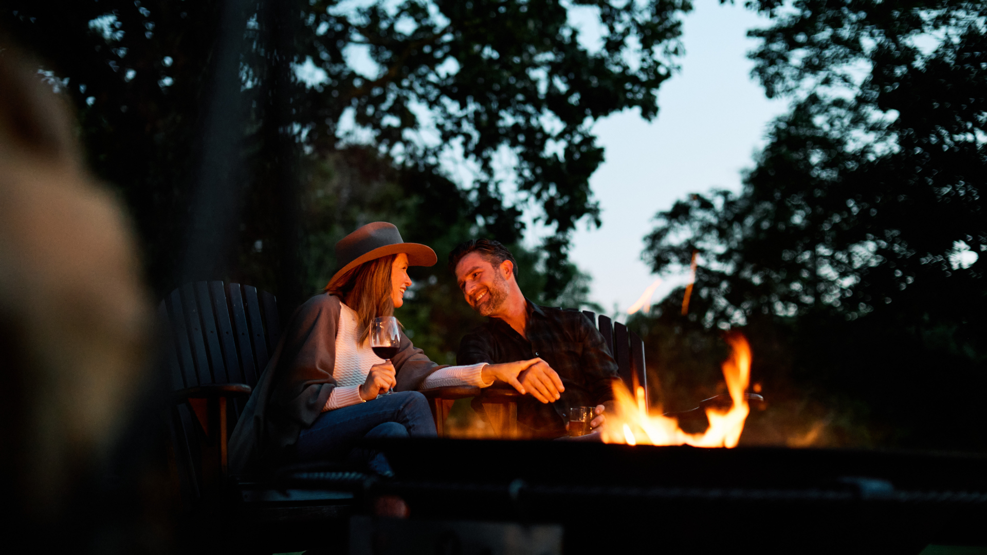 A man and woman holding hands by a firepit