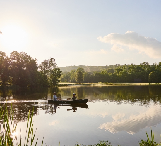 View of a pond with people paddling in two canoes.