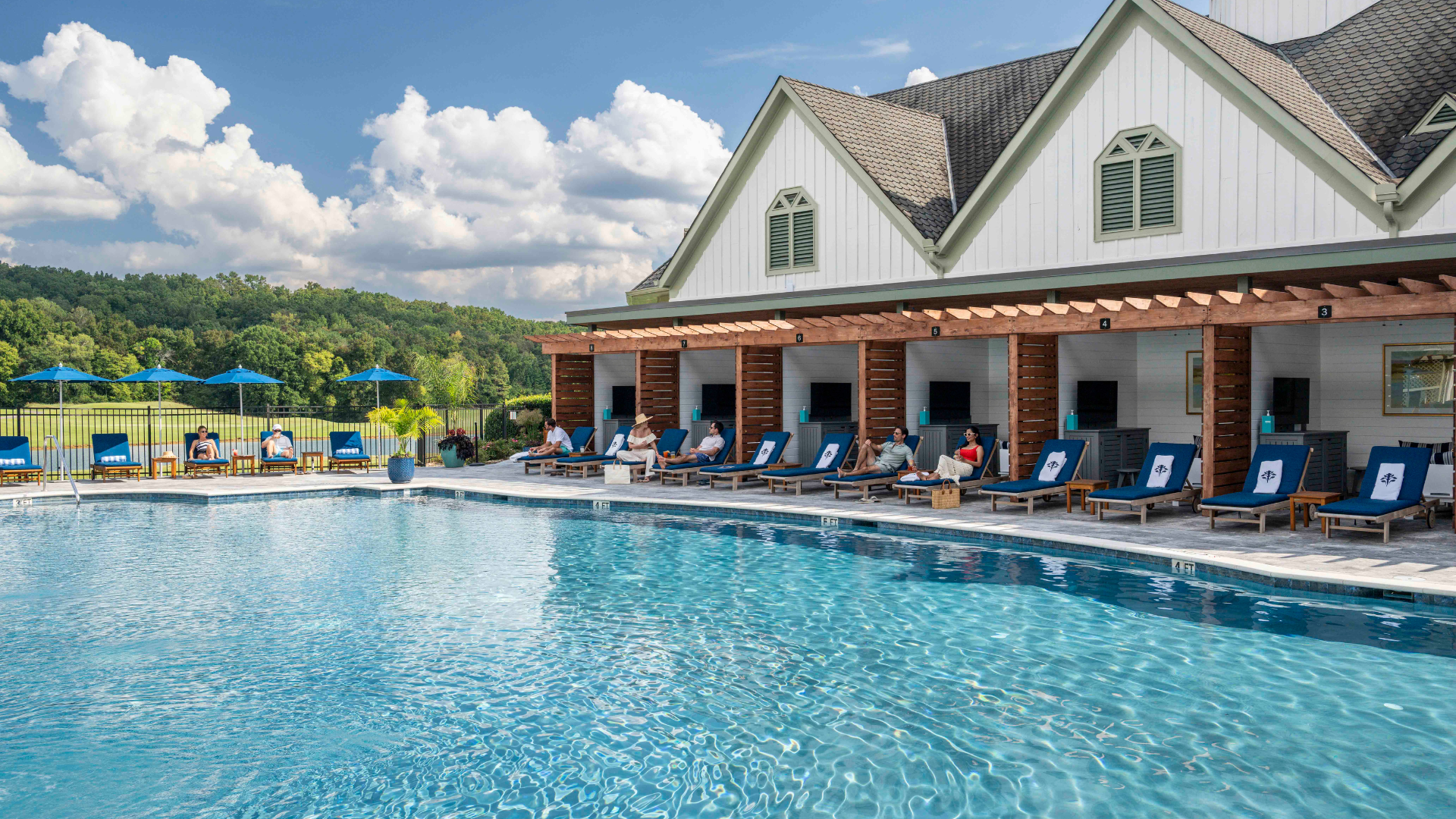 resort pool with cabanas and guests sunbathing and swimming