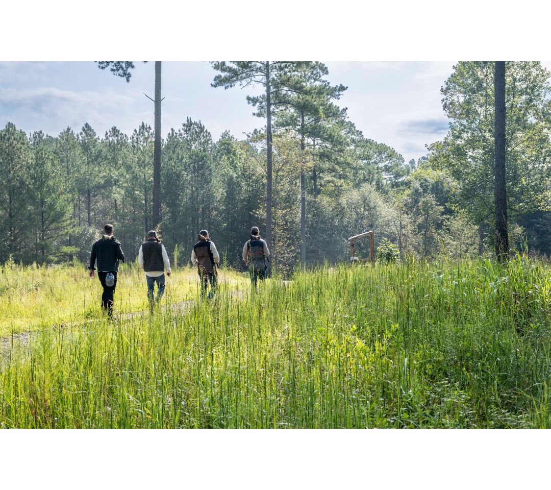 men walking in field with shotguns