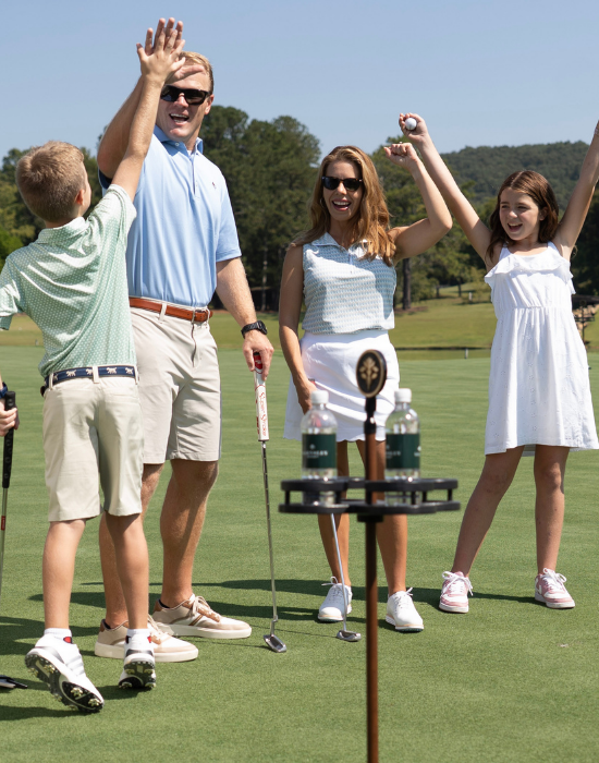 man, woman, girl and boy cheering on a putting course
