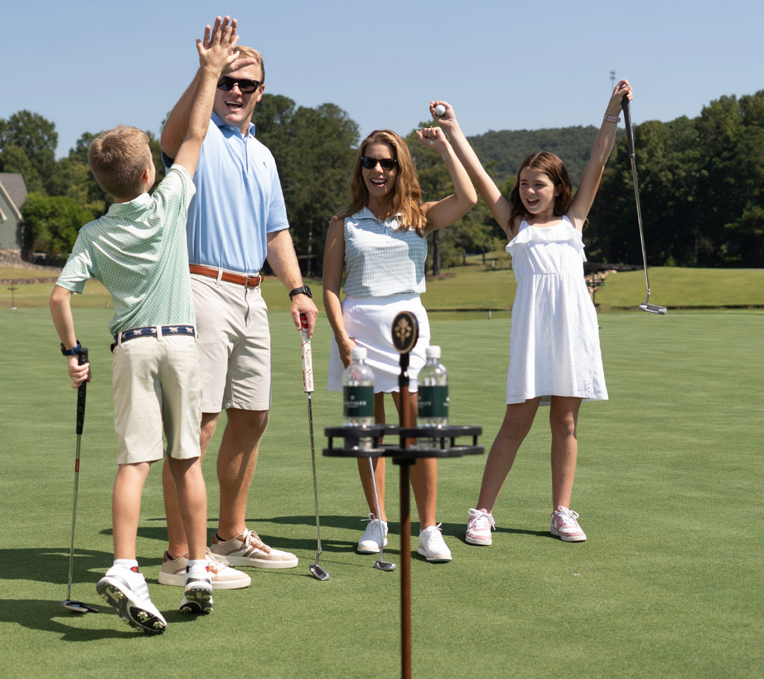 man, woman, girl and boy cheering on a putting course