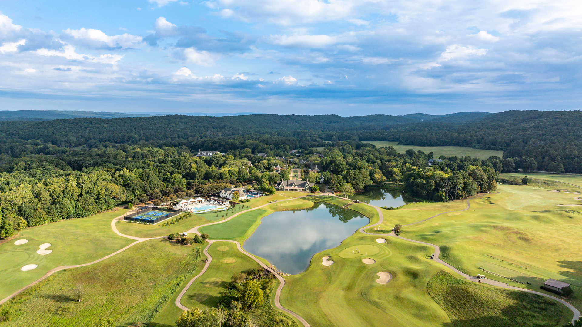 aerial of resort pools, pickleball courts, buildings, and golf course.