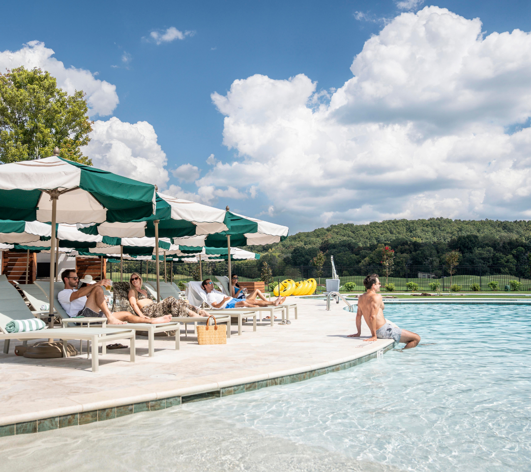 people lounging on chairs under green and white umbrellas