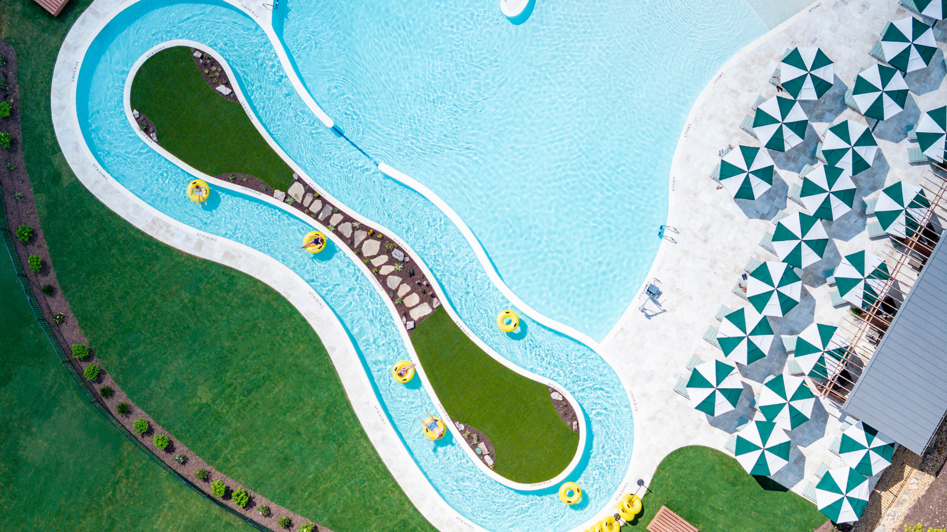 aerial view of a pool with a lazy river and striped umbrellas