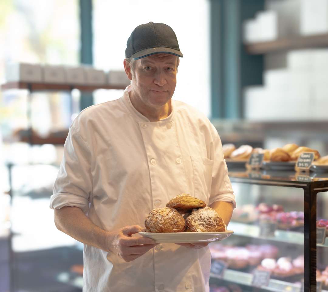 man in white coat holding a plate of pastries