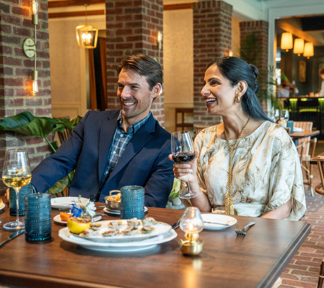 man and woman at a table, with plates of food and glasses