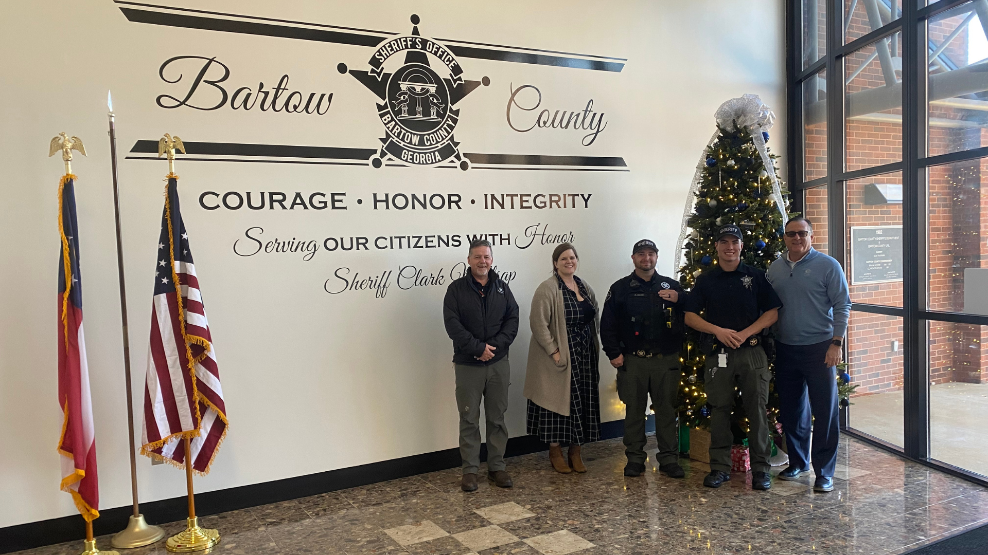 men and woman in uniforms in front of entryway of police station
