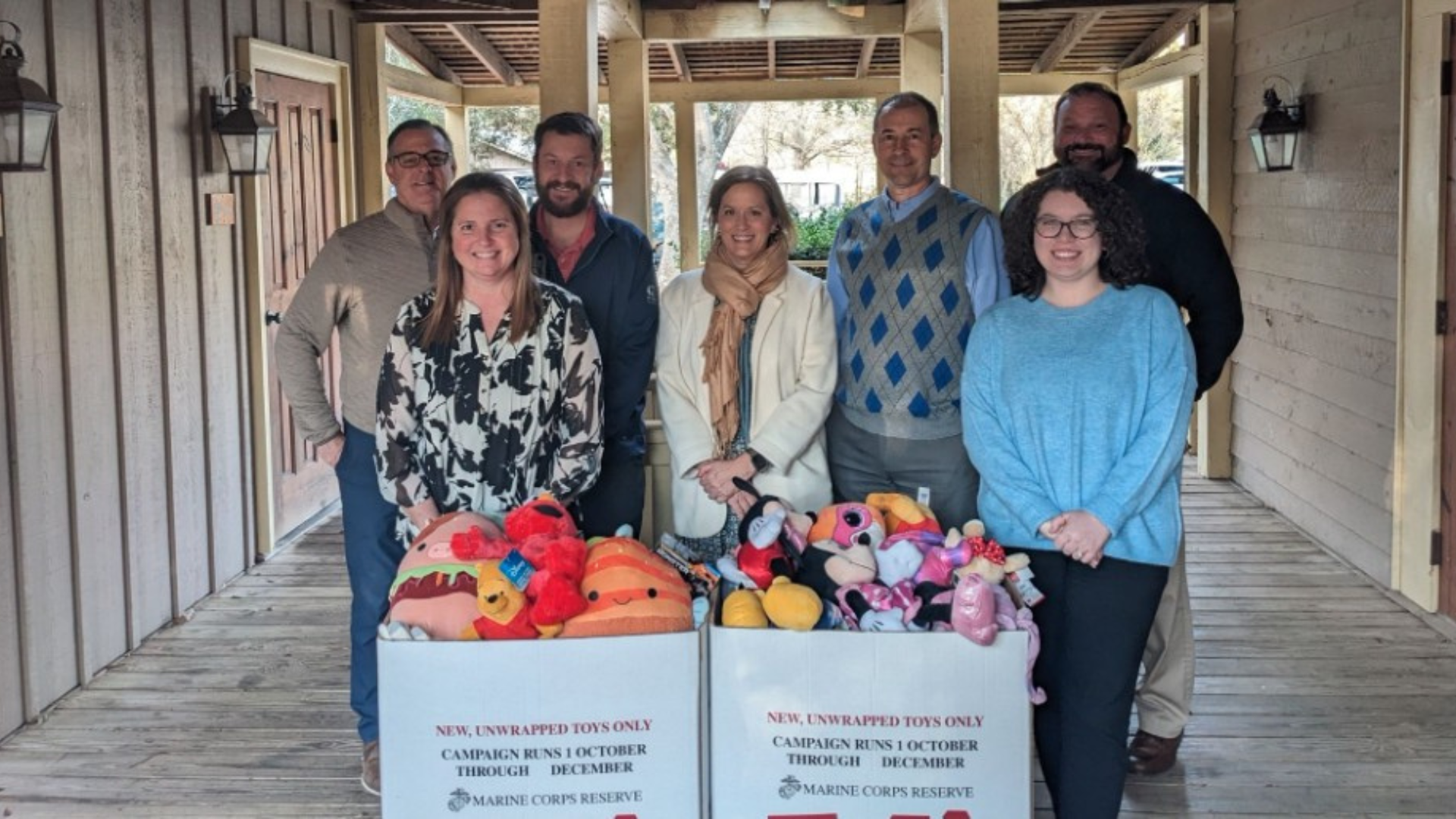 men and women behind a box of toys