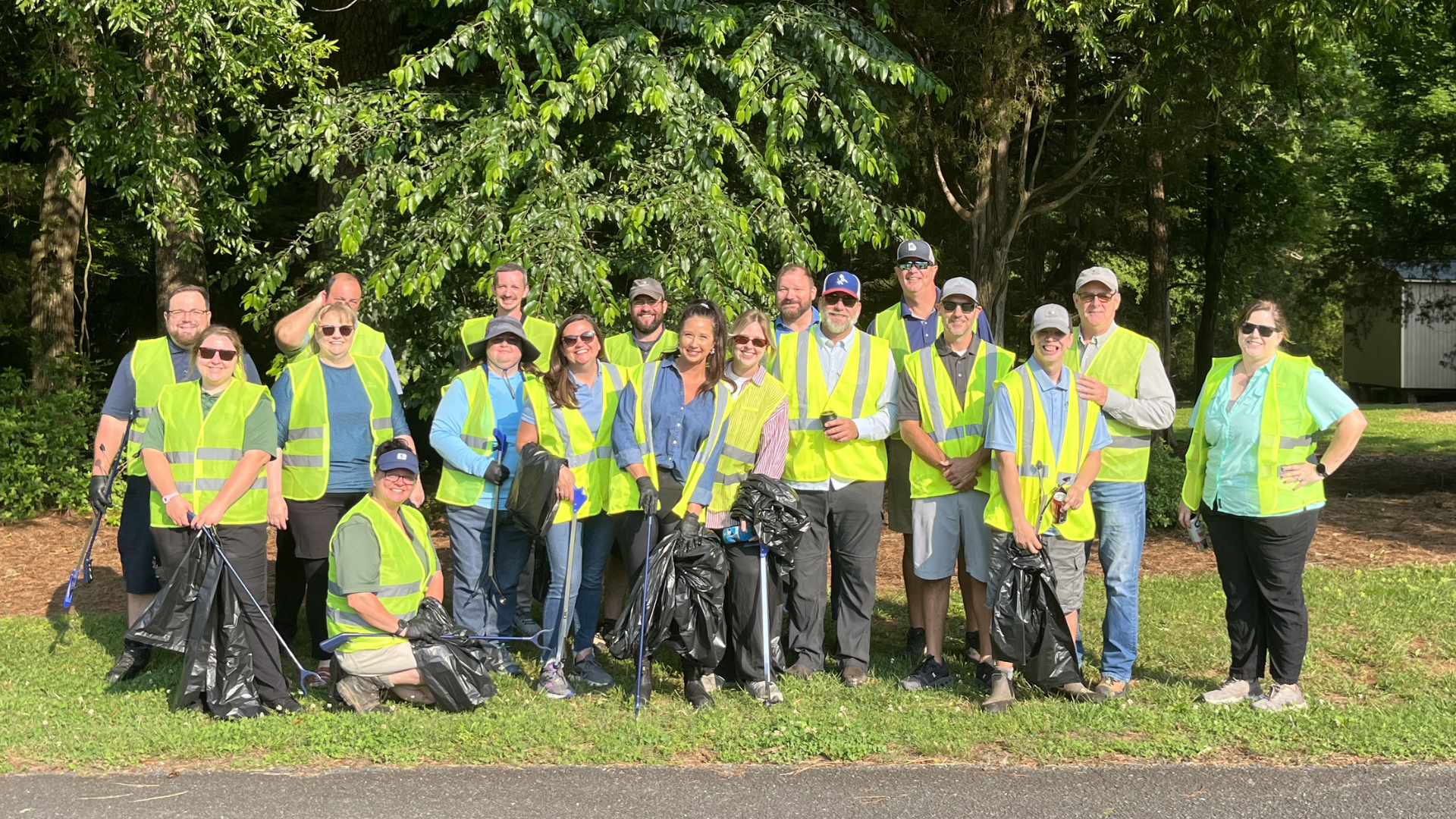 group of men and women in safety vests and trash grabbing tools