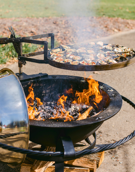 A grill with a tray of oysters grilling