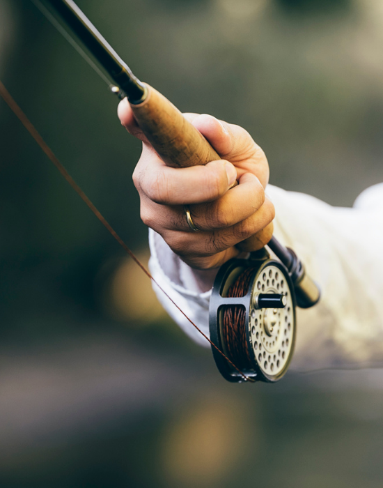 Close up of a hand holding a fly fishing pole