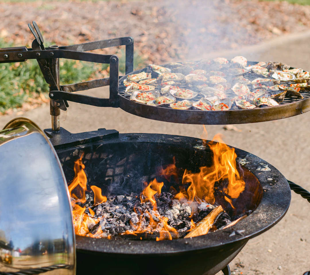 A grill with a tray of oysters grilling