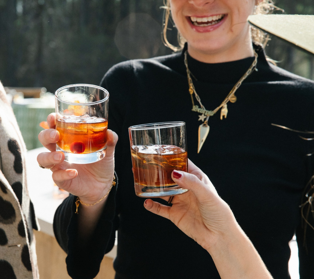two woman clinking cocktails in glasses
