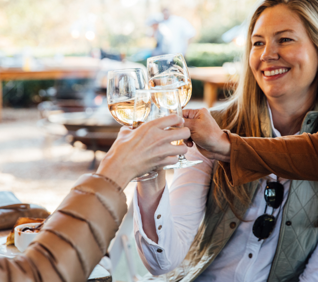 three hands holding wine, toasting. Woman smiling in background