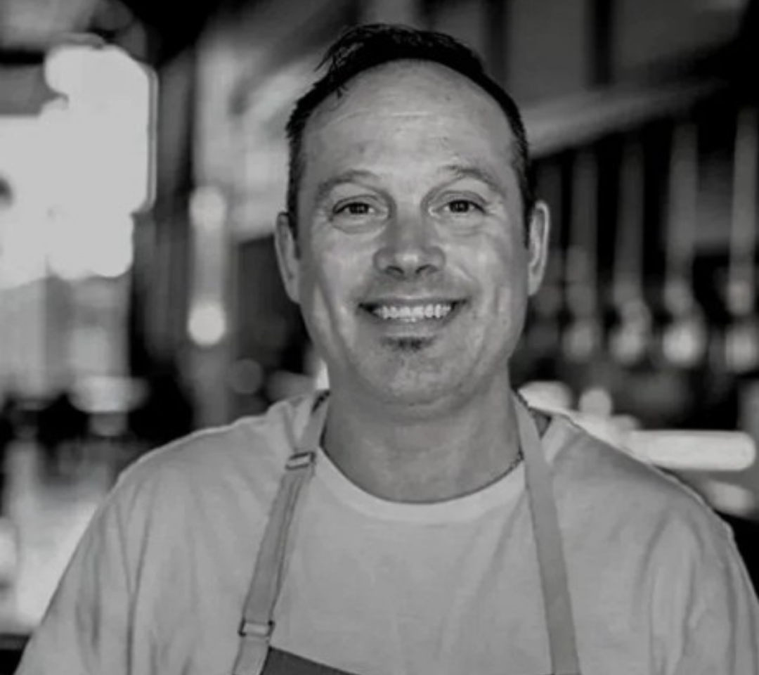 man in chef's coat smiling at camera