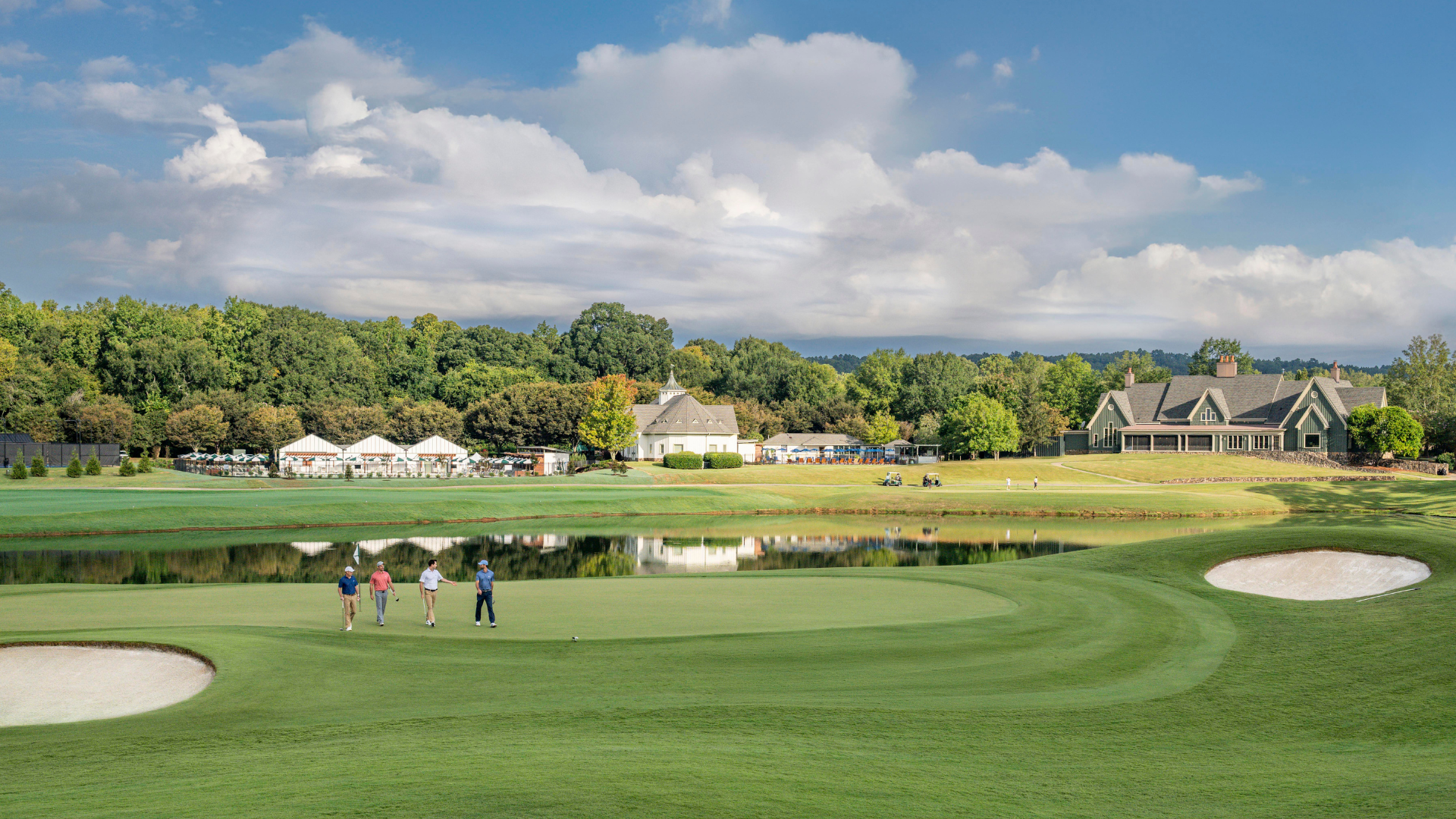 four men walking across a golf course