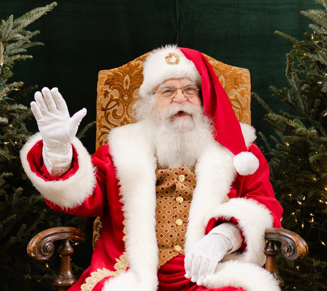 a man in red suit and white beard waving at camera