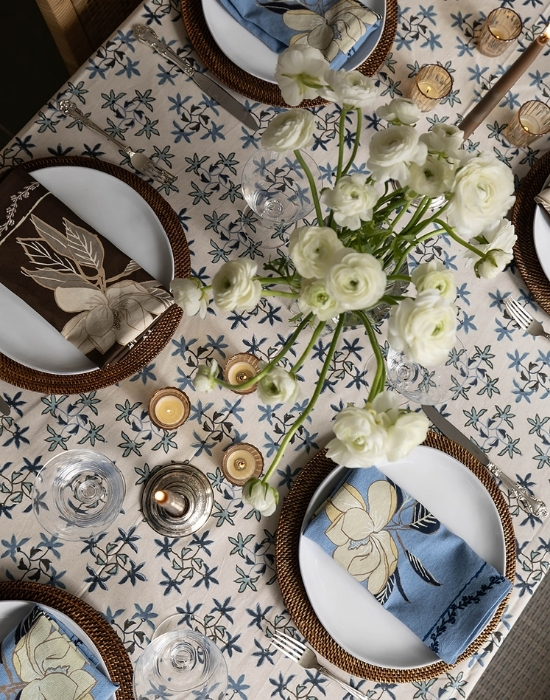 tablescape of patterned tablecloth with flowers and plates and cutlery