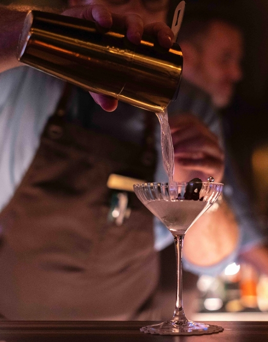 a man pouring a cocktail into a glass