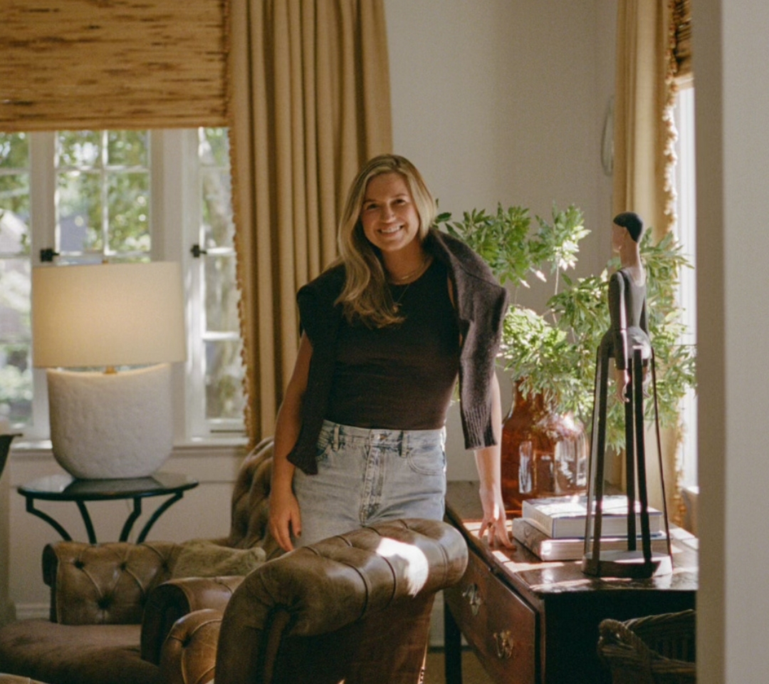 woman standing in the middle of a furnished room, smiling at camera