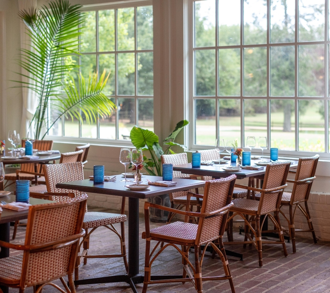 room of table and chairs with large windows and plants
