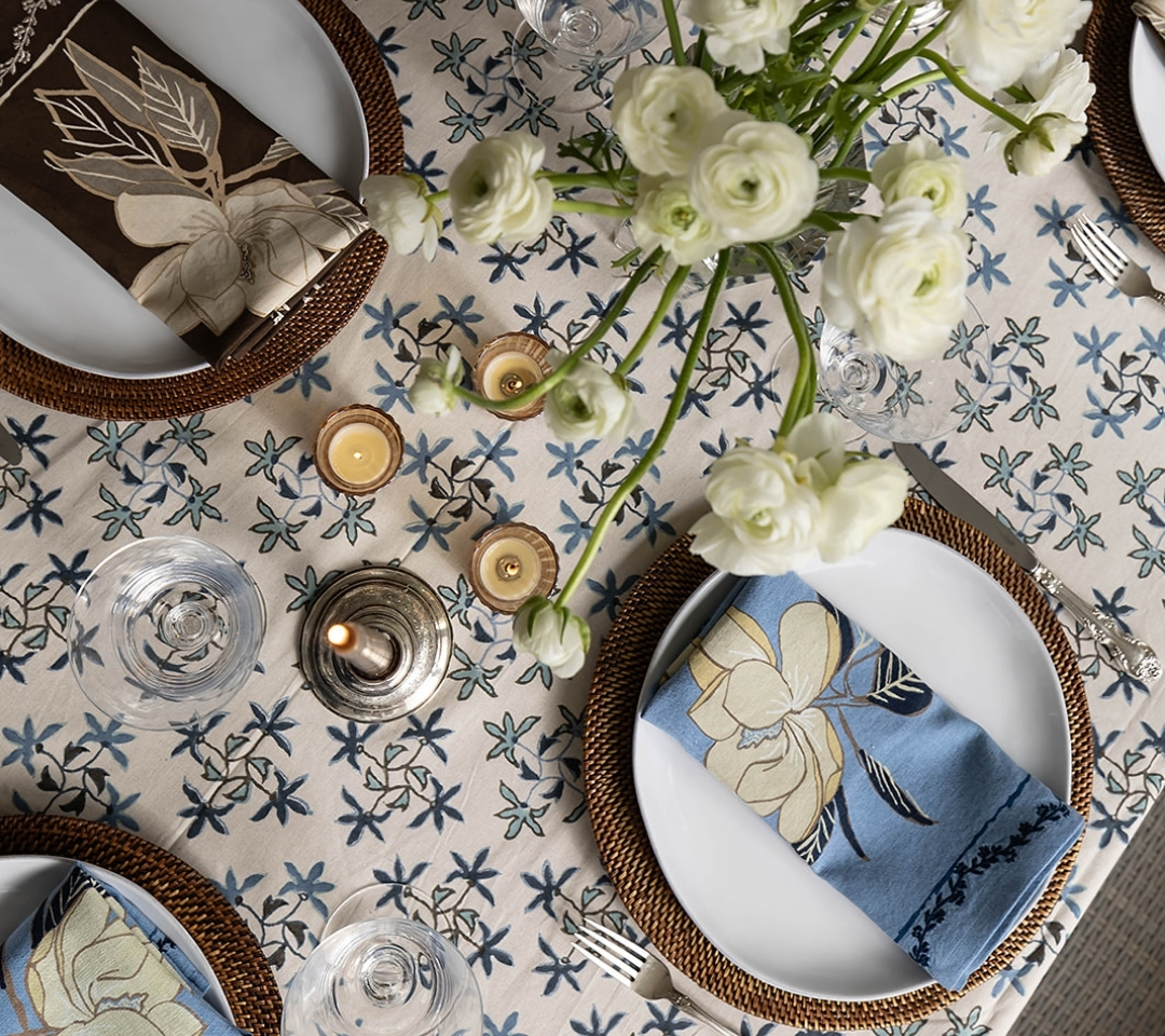 tablescape of patterned tablecloth with flowers and plates and cutlery