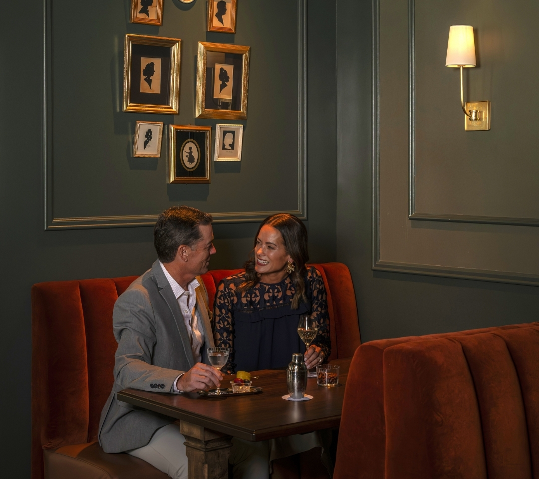couple sitting at restaurant table, smiling at each other