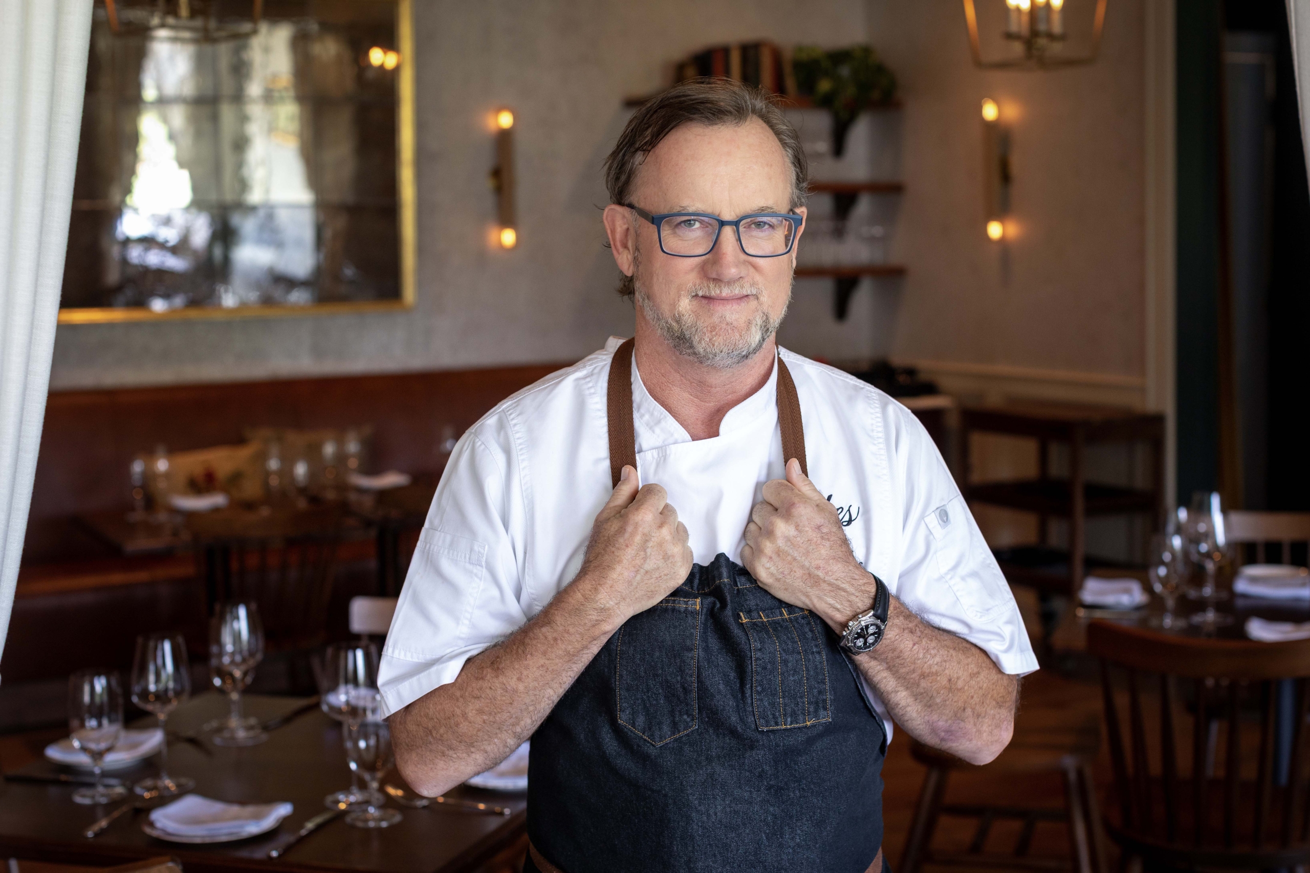 man in chef's apron with hands holding apron straps