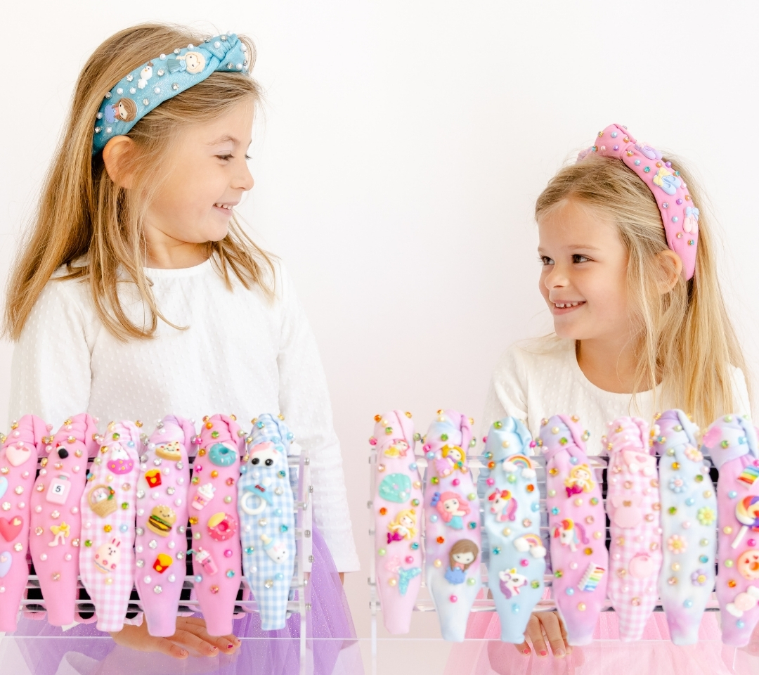 two girls standing behind a row of colorful headbands