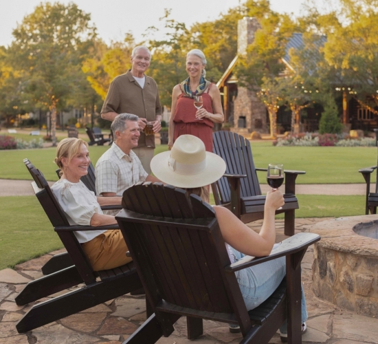 a group of adults sitting around a fire pit