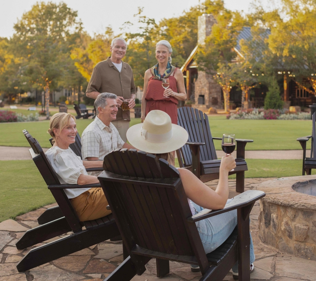 a group of adults sitting around a fire pit