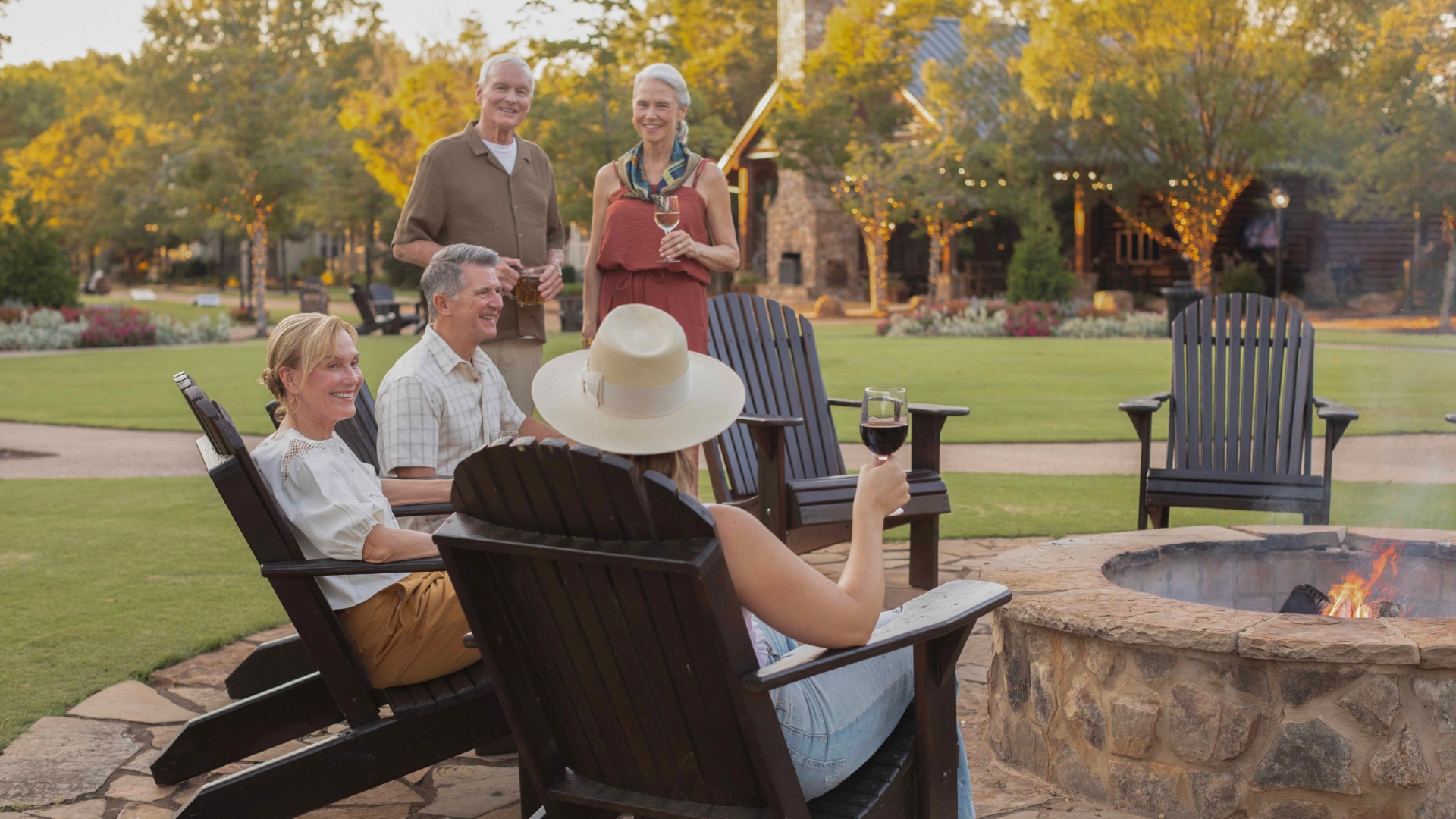 a group of adults sitting around a fire pit