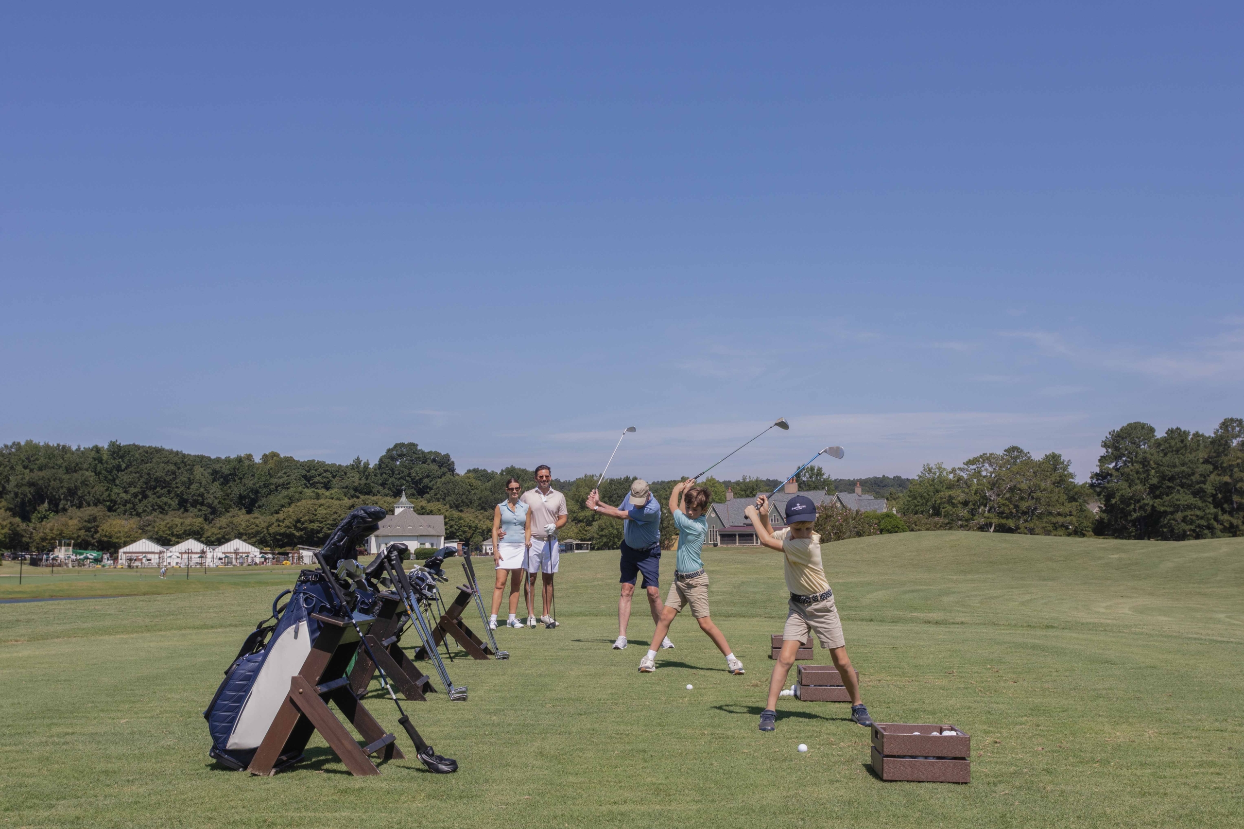 a driving range and people swing golf clubs